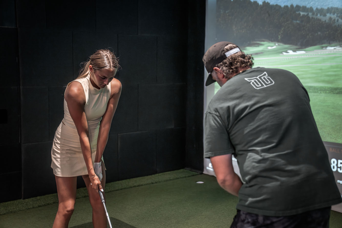 An image of a woman working with a Tee Box golf swing coach.