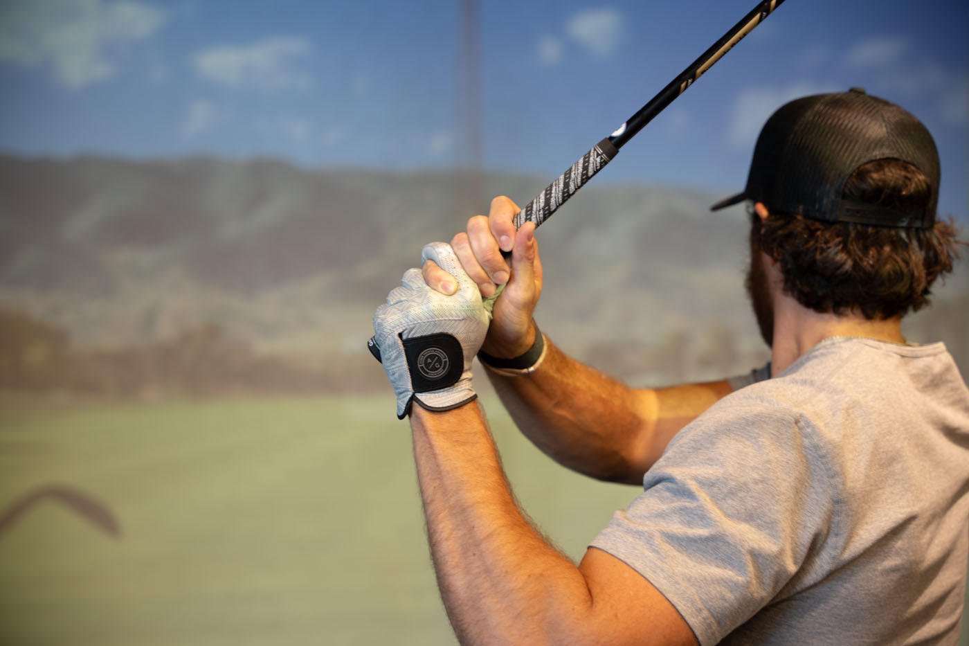 An Tee Box member practicing his golf swin on a trackman golf sim.