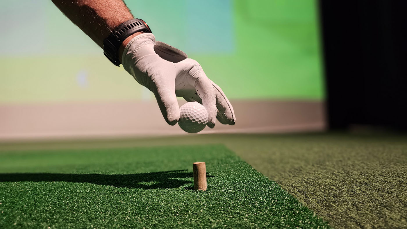 An image of a person teeing up a golf ball at Tee Box Georgetown.