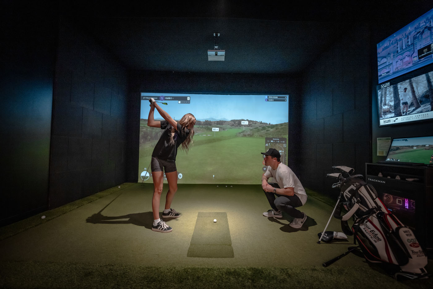 A golfer receiving professional golf training at an indoor Tee Box facility.