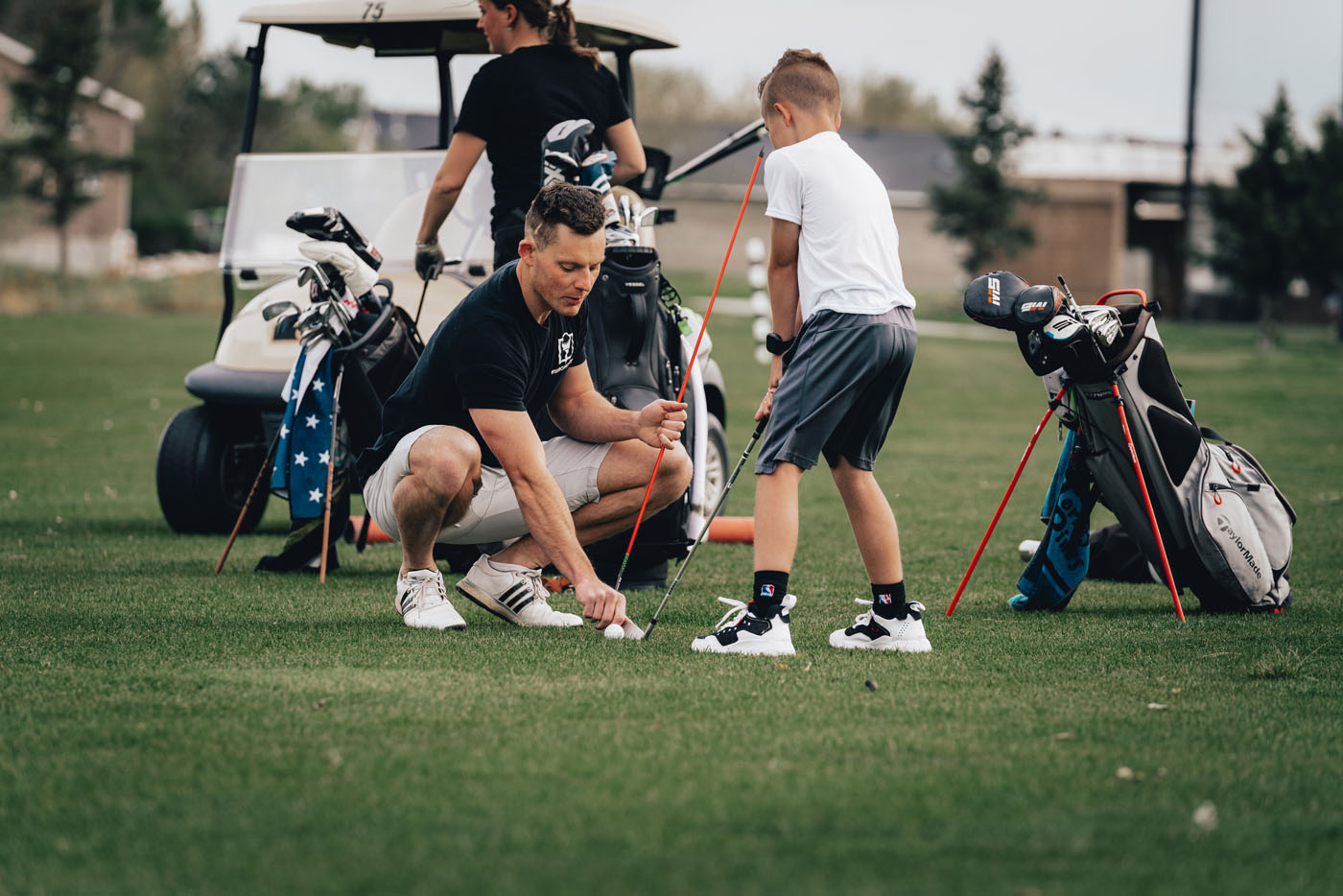 A Tee Box golf instructor in St. George, UT helping a younger golfer on our outside course.