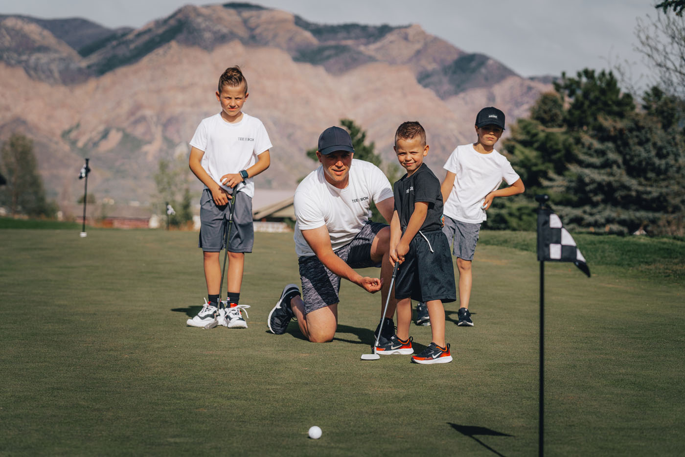 A group of kids having fun and playing golf at Tee Box, one of the top childrens party venues.