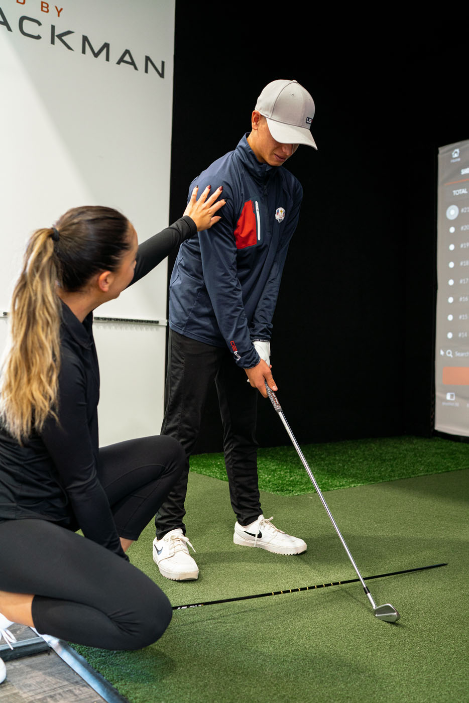 A trainer working with a young boy on his swing.