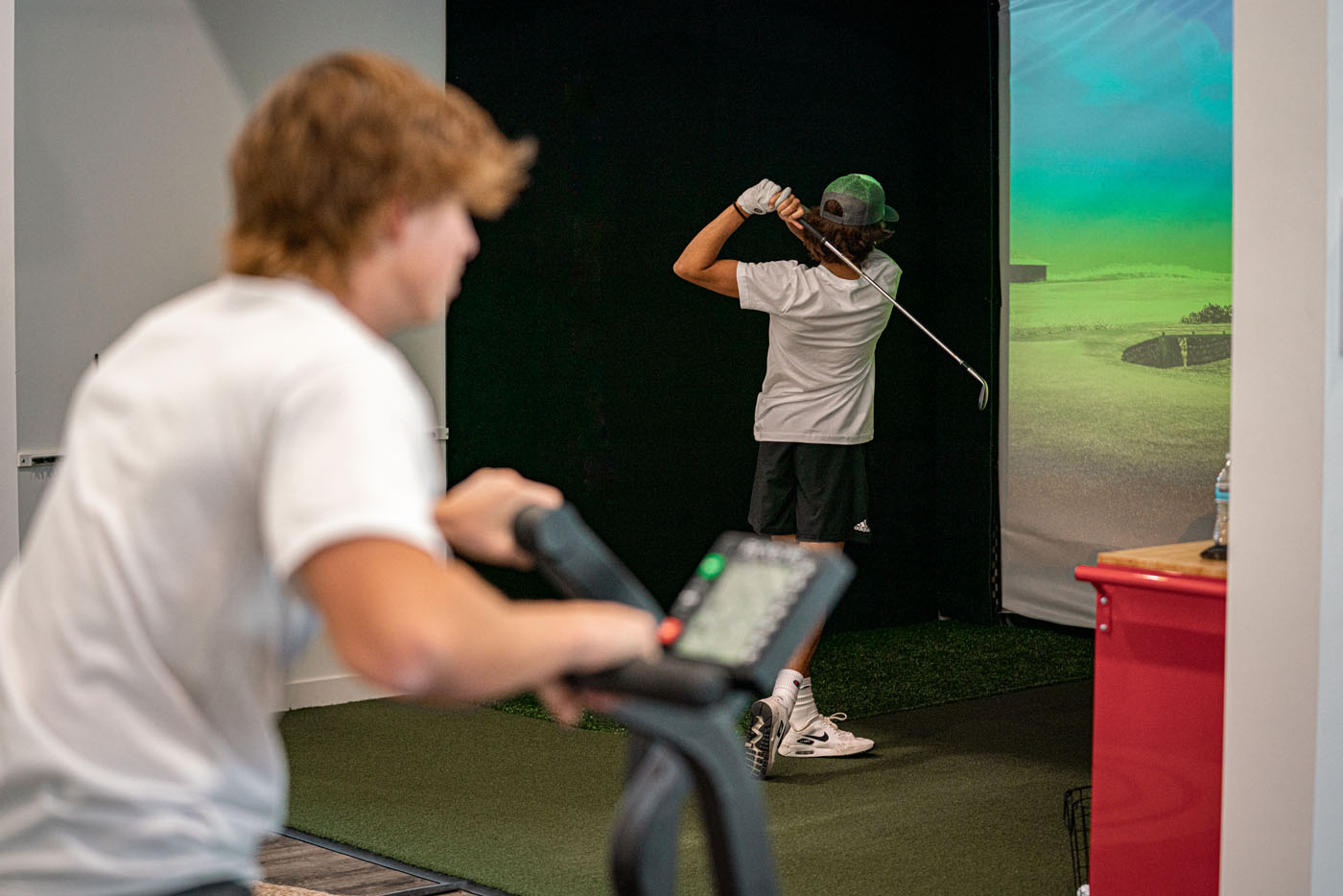 Two Tee Box members working out at our indoor golf simulator in St. George, UT.